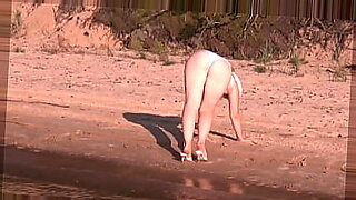 Uma loira sexy encharcada de sol tira a roupa à beira-mar.